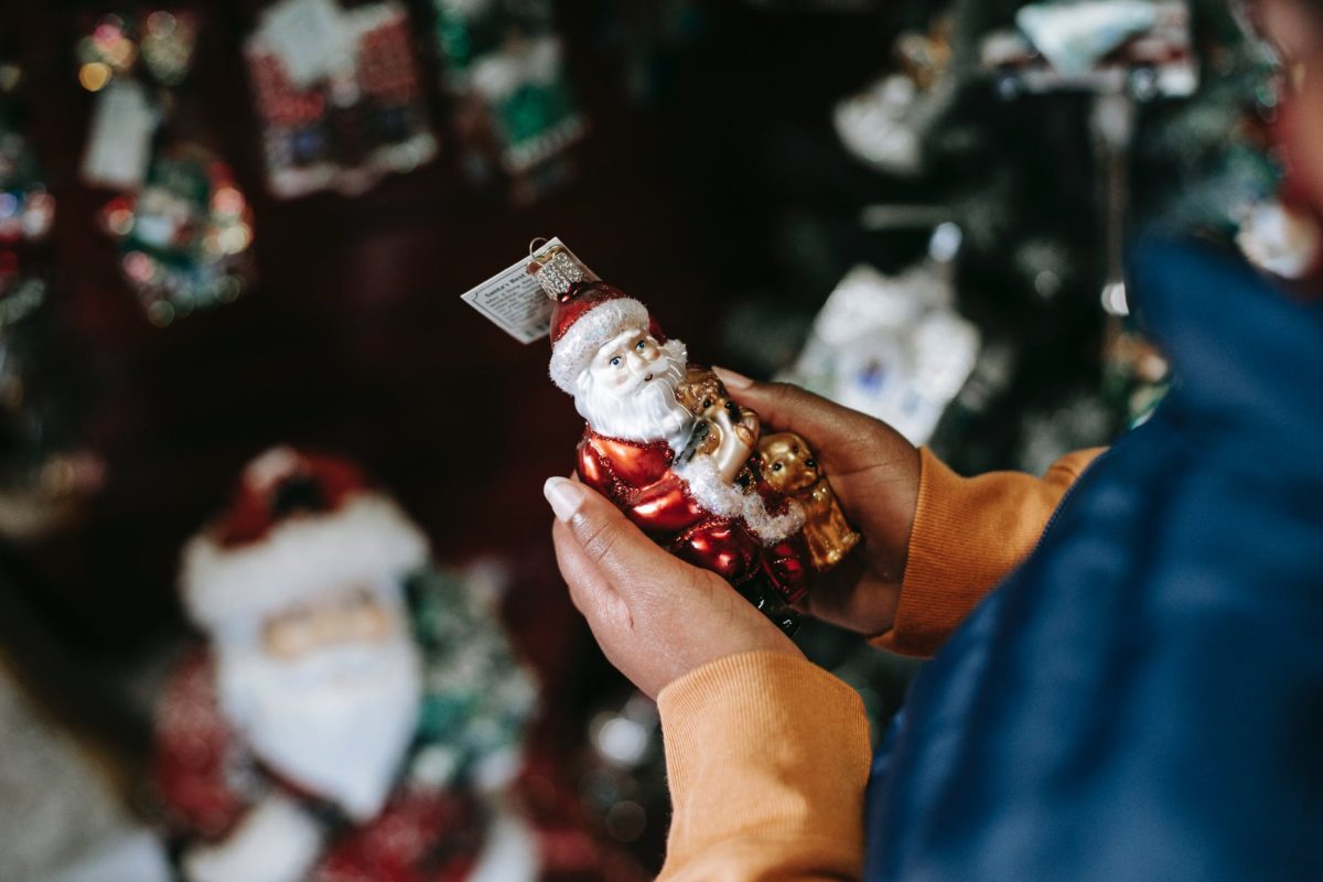 crop black person with decorative santa claus in shop