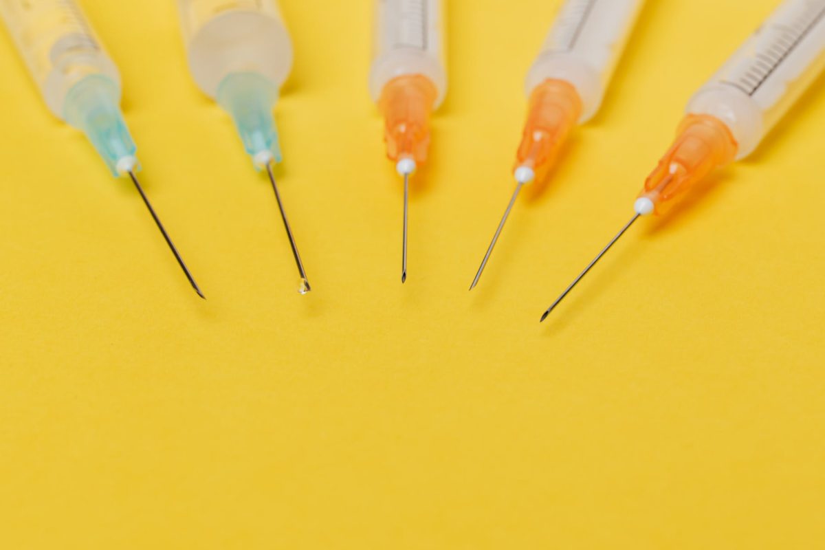 syringe needles with no cover on yellow background