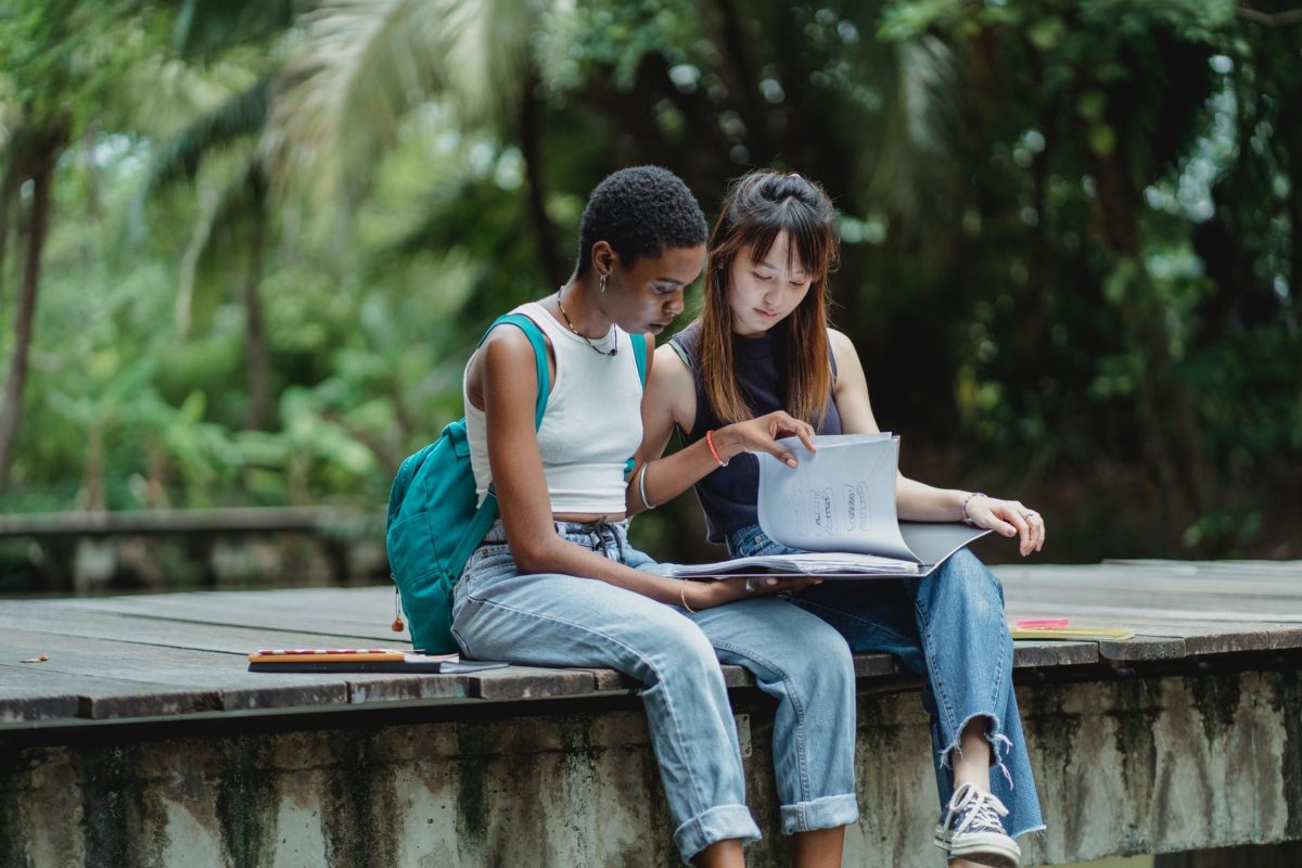 young concentrated diverse students studying together in park