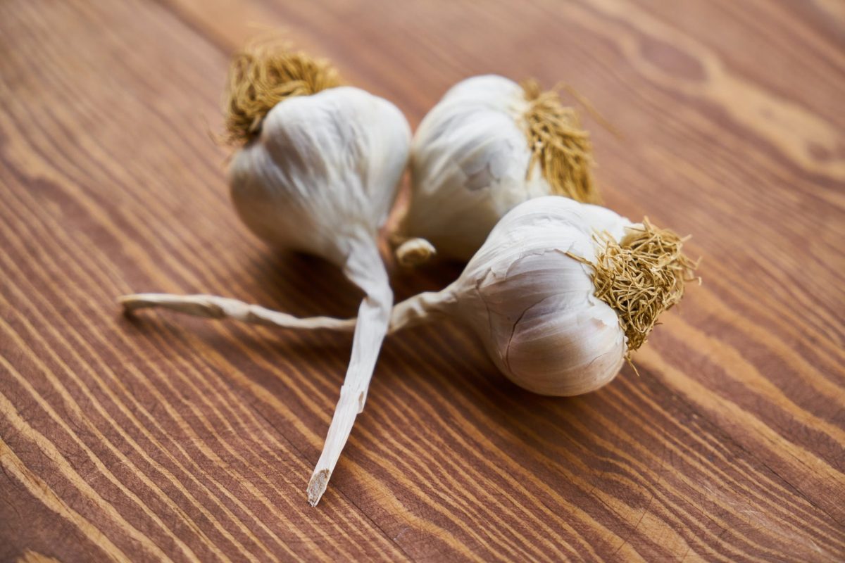 close up photo of three garlic on wooden surface