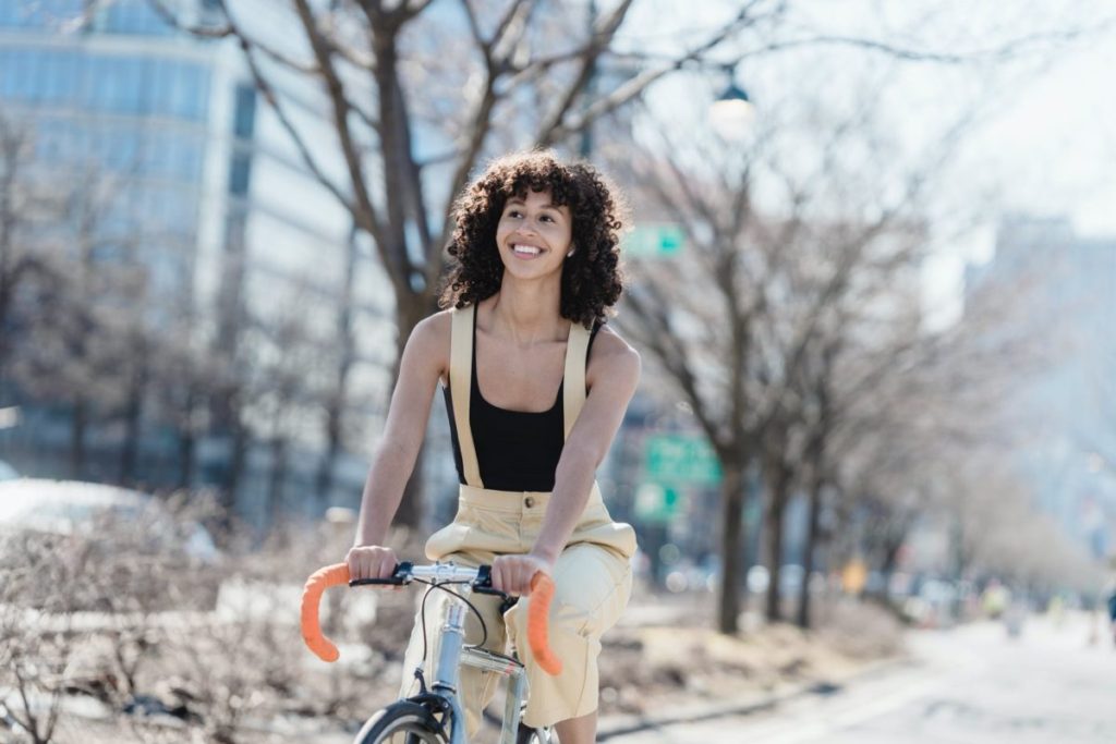 happy ethnic woman riding bicycle on street