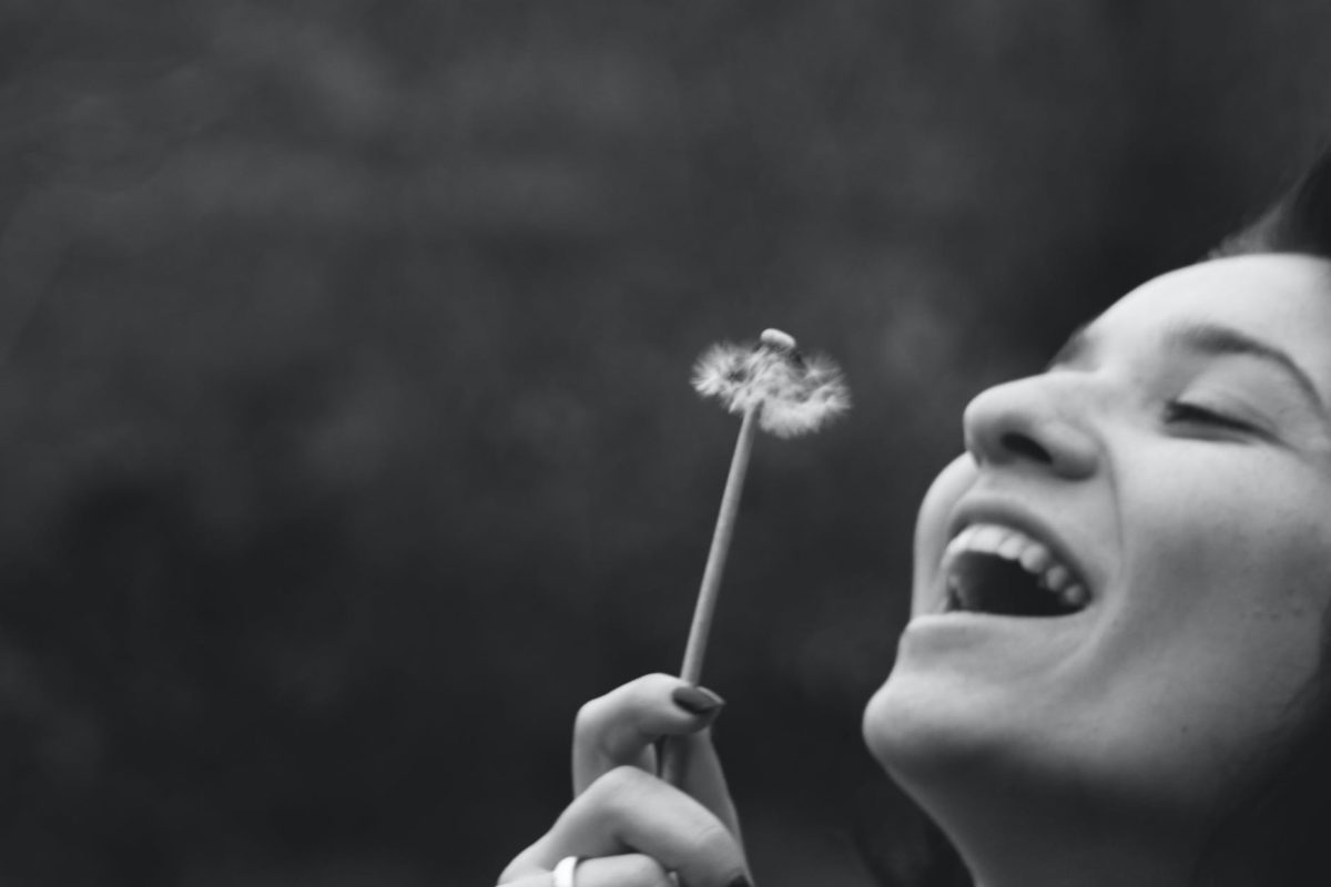 smiling woman holding dandelion flower