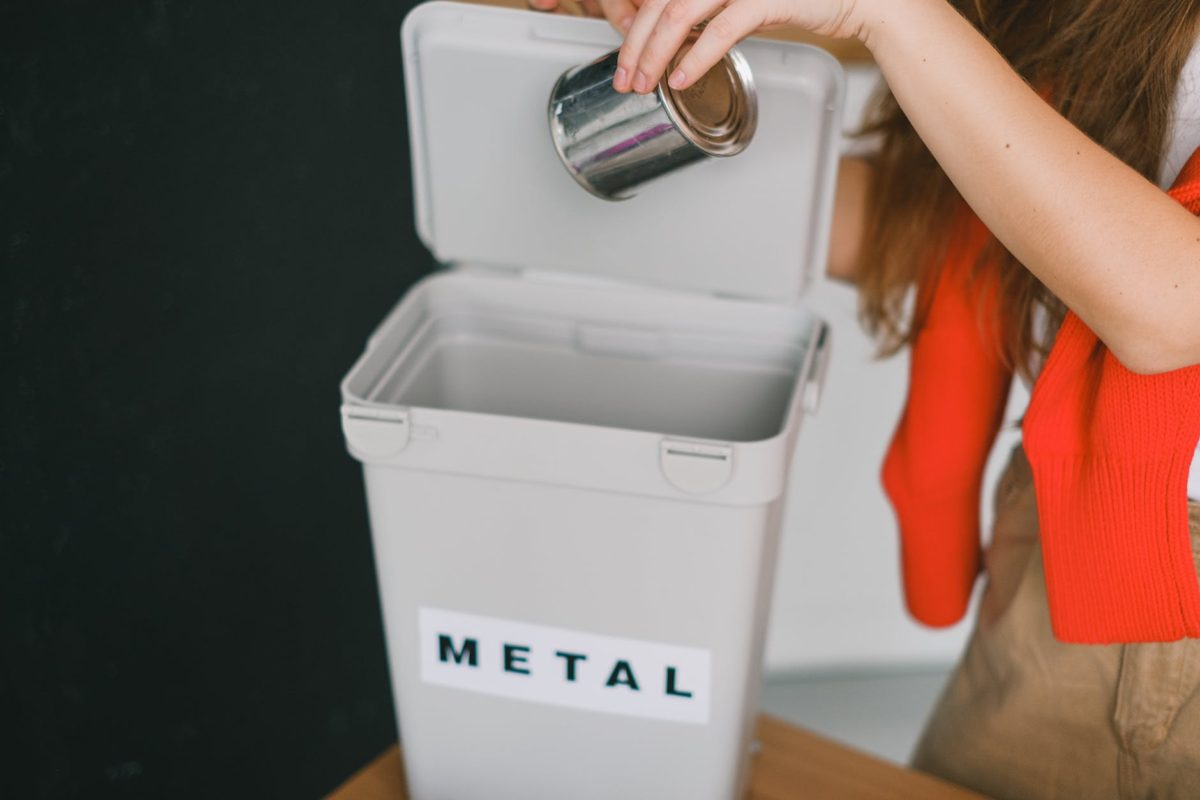 woman sorting garbage and putting metal can into bucket